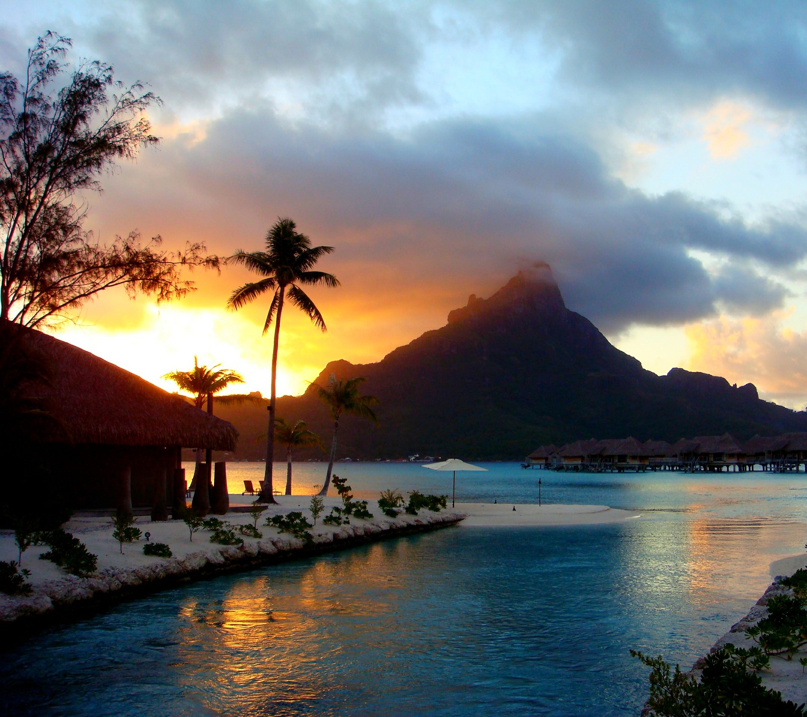 Sunset over a body of water with a hut and palm trees (beach, bora bora, paradise, sea, sunset)