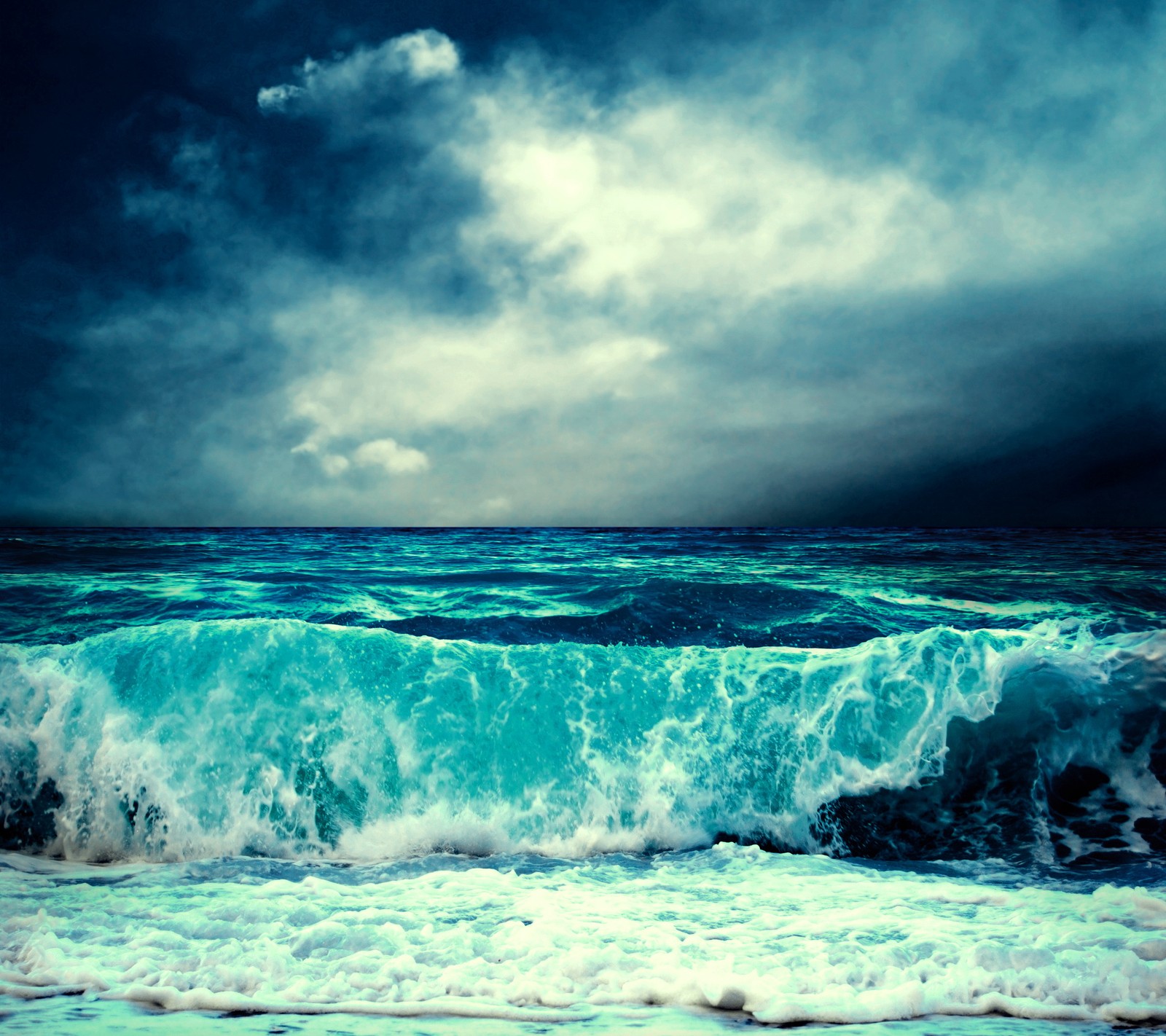 Un gros plan d'une vague se brisant sur une plage sous un ciel nuageux (vagues de mer, nuages dans le ciel, stormy weather, eau)