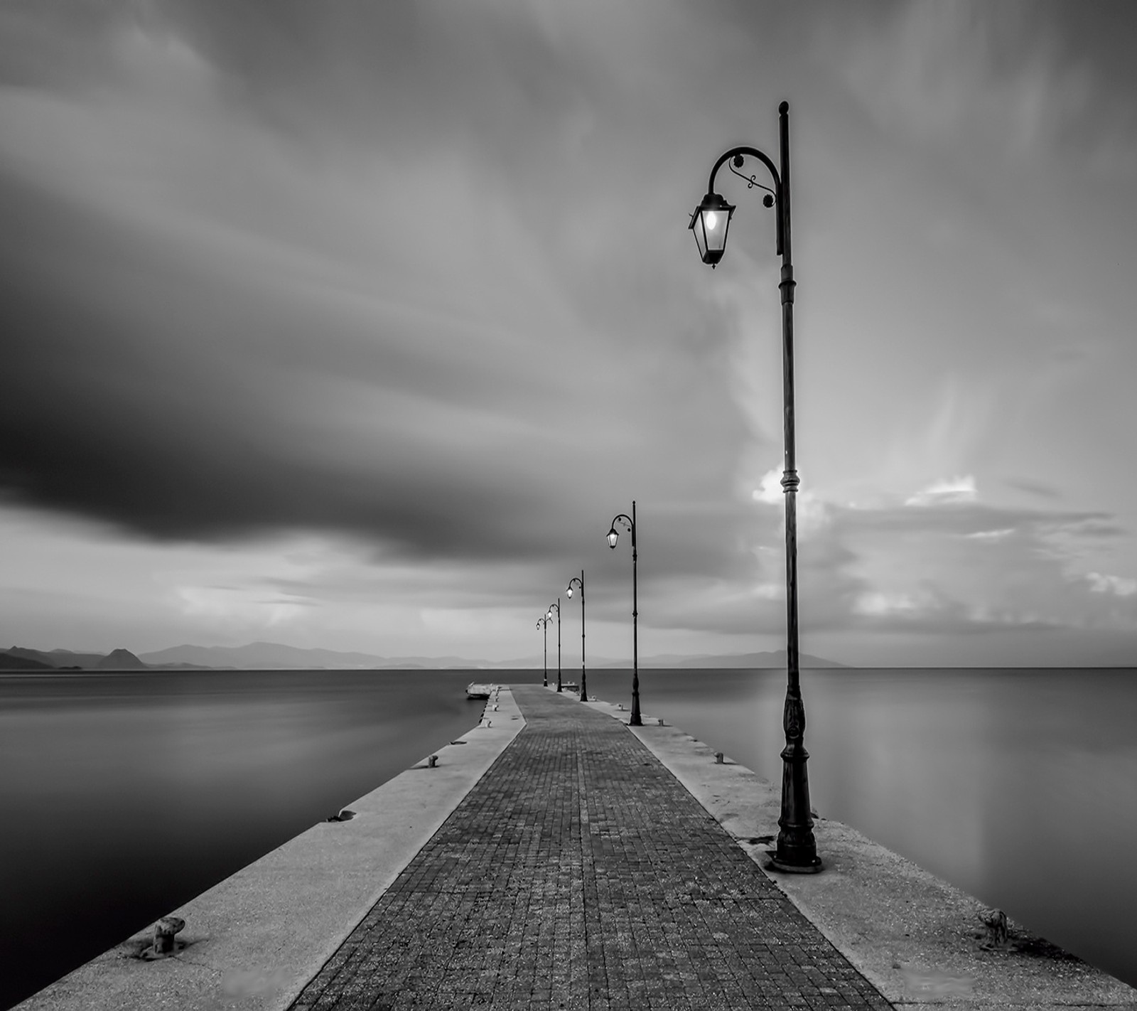 Foto en blanco y negro de un muelle con un farol y un banco (blanco y negro, nublado, gris, luces, ánimo)