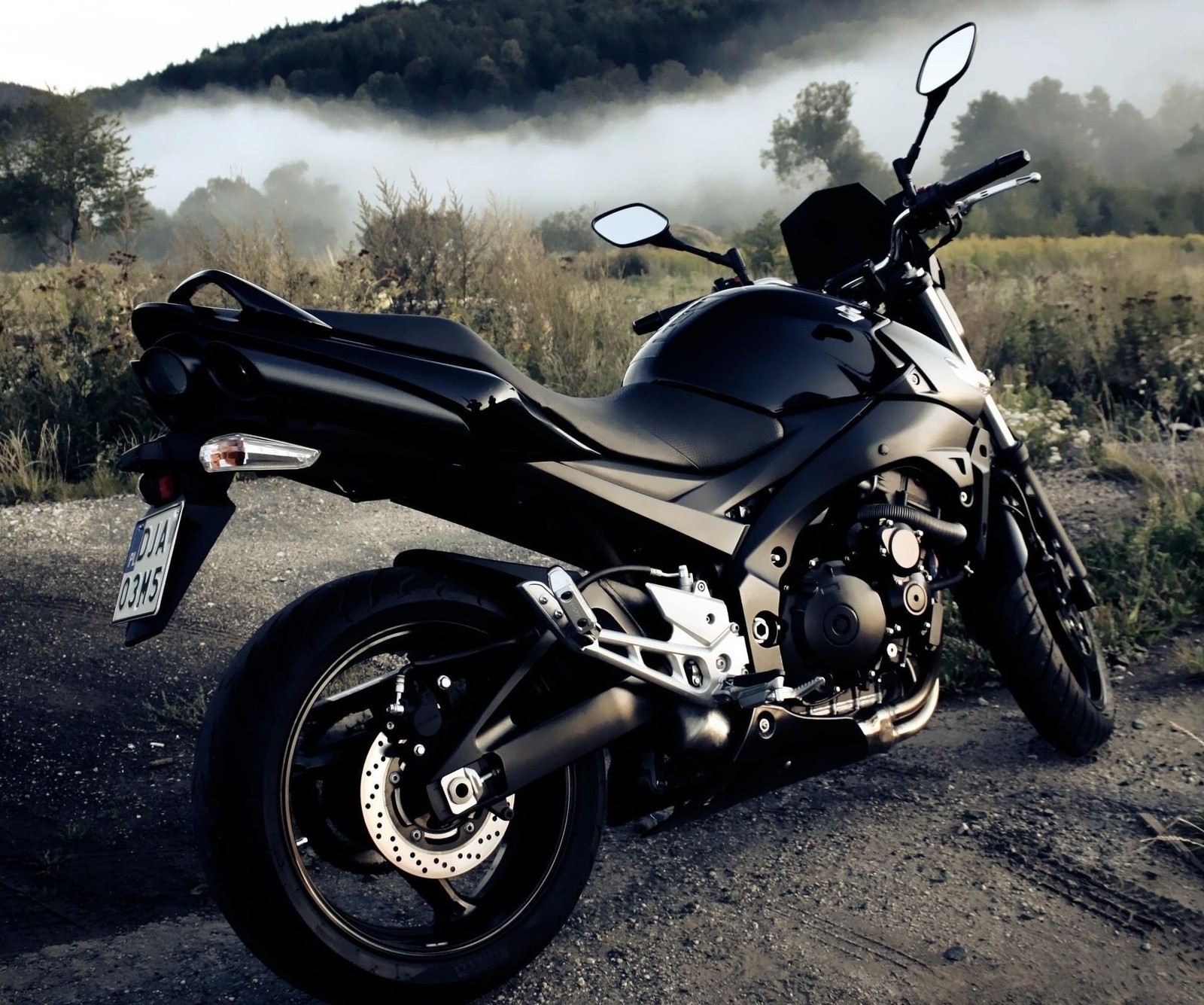 Motorcycle parked on a dirt road in front of a mountain (bike, black thunder)