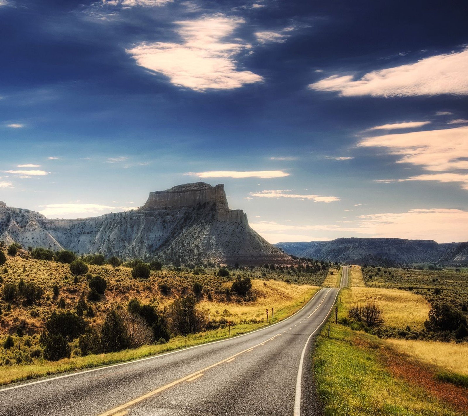 Uma estrada asfaltada com uma montanha ao fundo e um céu com nuvens (nuvens, deserto, sujo, paisagem, natureza)