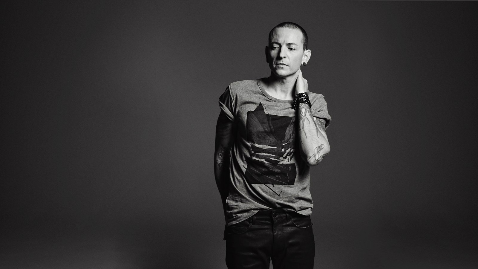 Un homme portant une keffieh en chemise grise et pantalon noir pose pour une photo. (chester bennington, linkin park, musique, debout, monochrome)