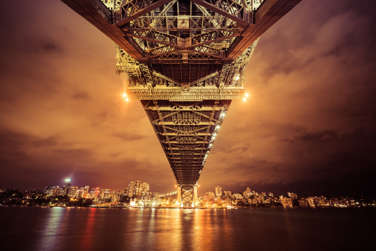 Uma vista de uma ponte sobre um corpo d'água à noite. (ponte da baía de sydney, iluminado, austrália, paisagem urbana, flúmen)