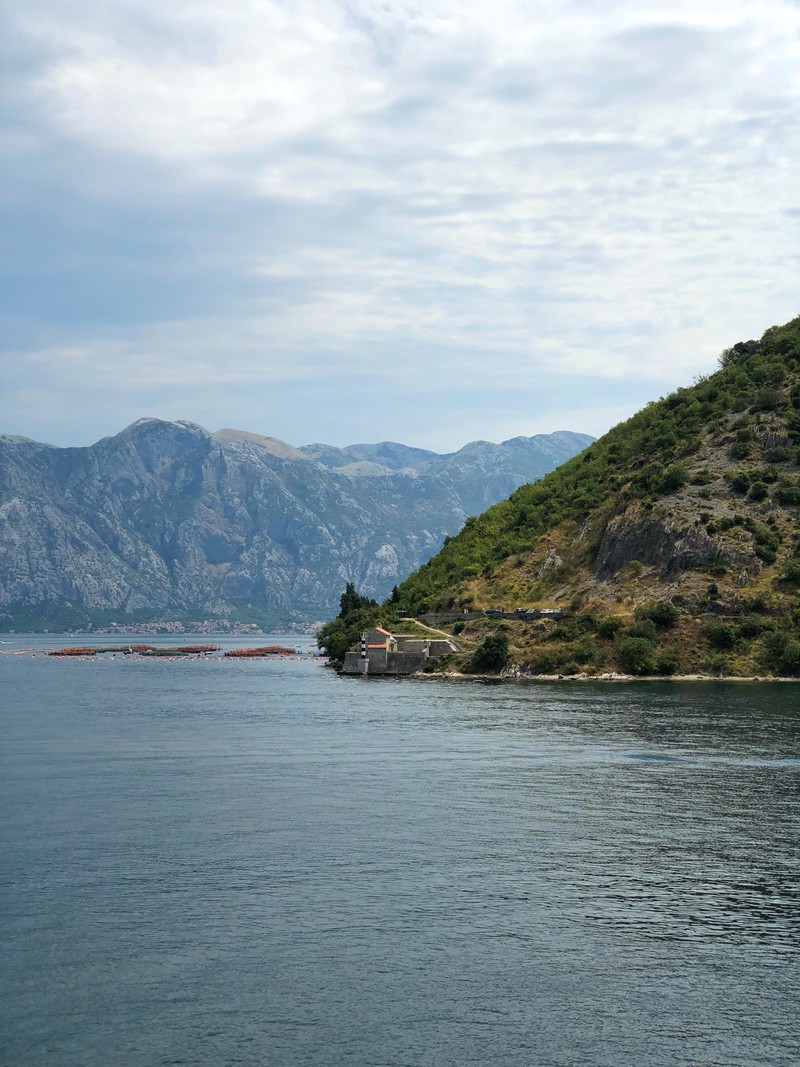 Маленькая лодка в воде рядом с горой (берег, общественное достояние, водоем, горные образования, водные ресурсы)