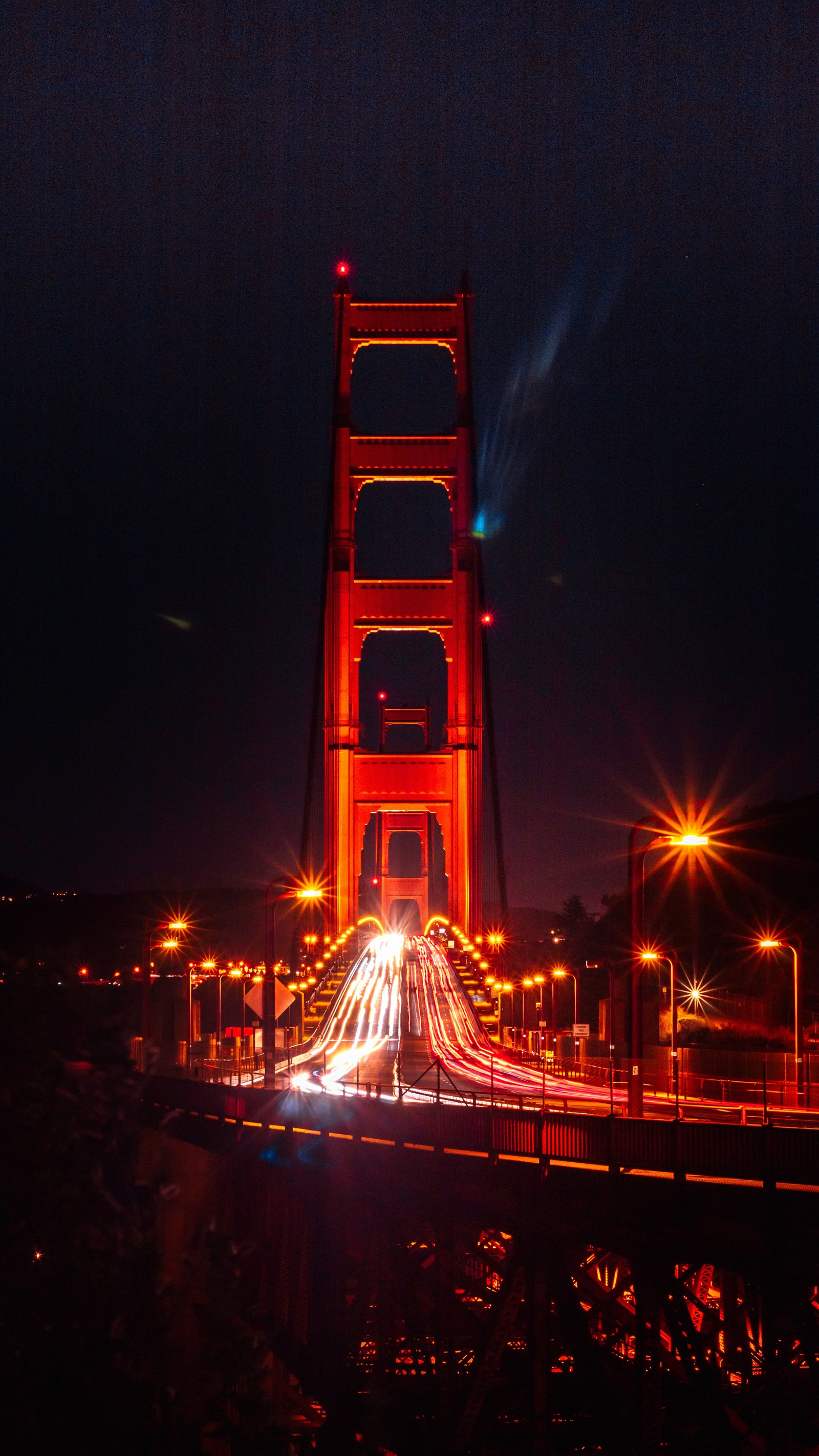 Vista panorámica de un puente con coches circulando por él de noche (noche, hito, rojo, ligero, torre)