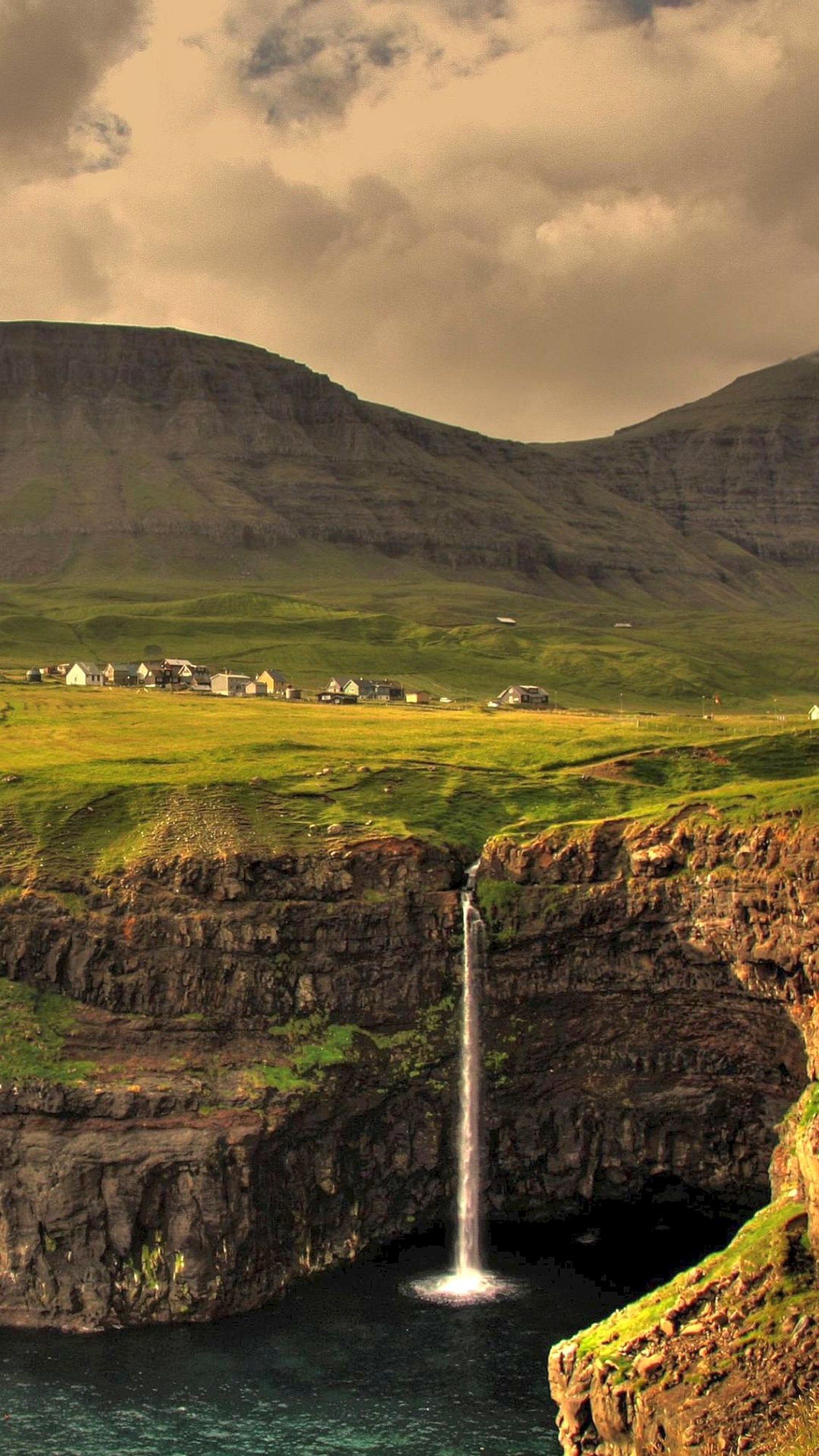 There is a waterfall in the middle of a large valley (falls, sea, village)