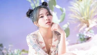 Chaeyoung de TWICE dans une pose sereine, entourée de douces couleurs pastel et d'éléments botaniques, reflétant l'esthétique de leur album "More & More".