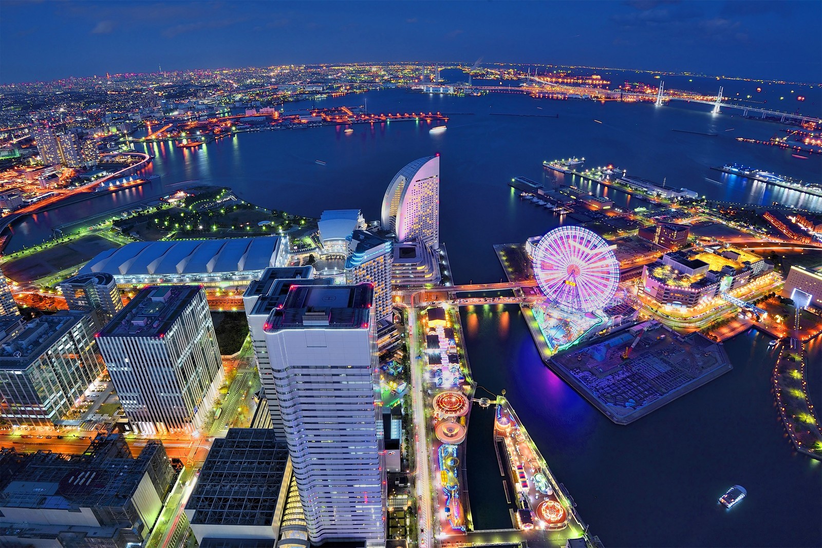 Blick auf eine stadt bei nacht mit einem riesenrad (yokohama landmark tower, wahrzeichen, stadtbild, stadtgebiet, stadt)