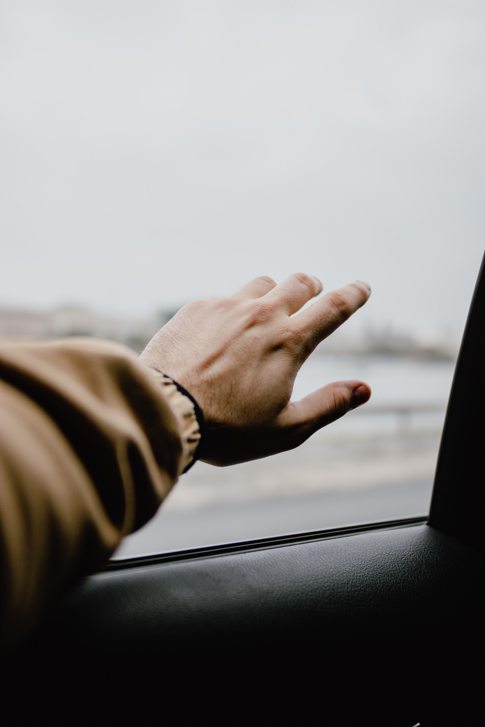 Alguém está segurando a mão para fora da janela de um carro (polegar, sentado, braço, dedo, céu)