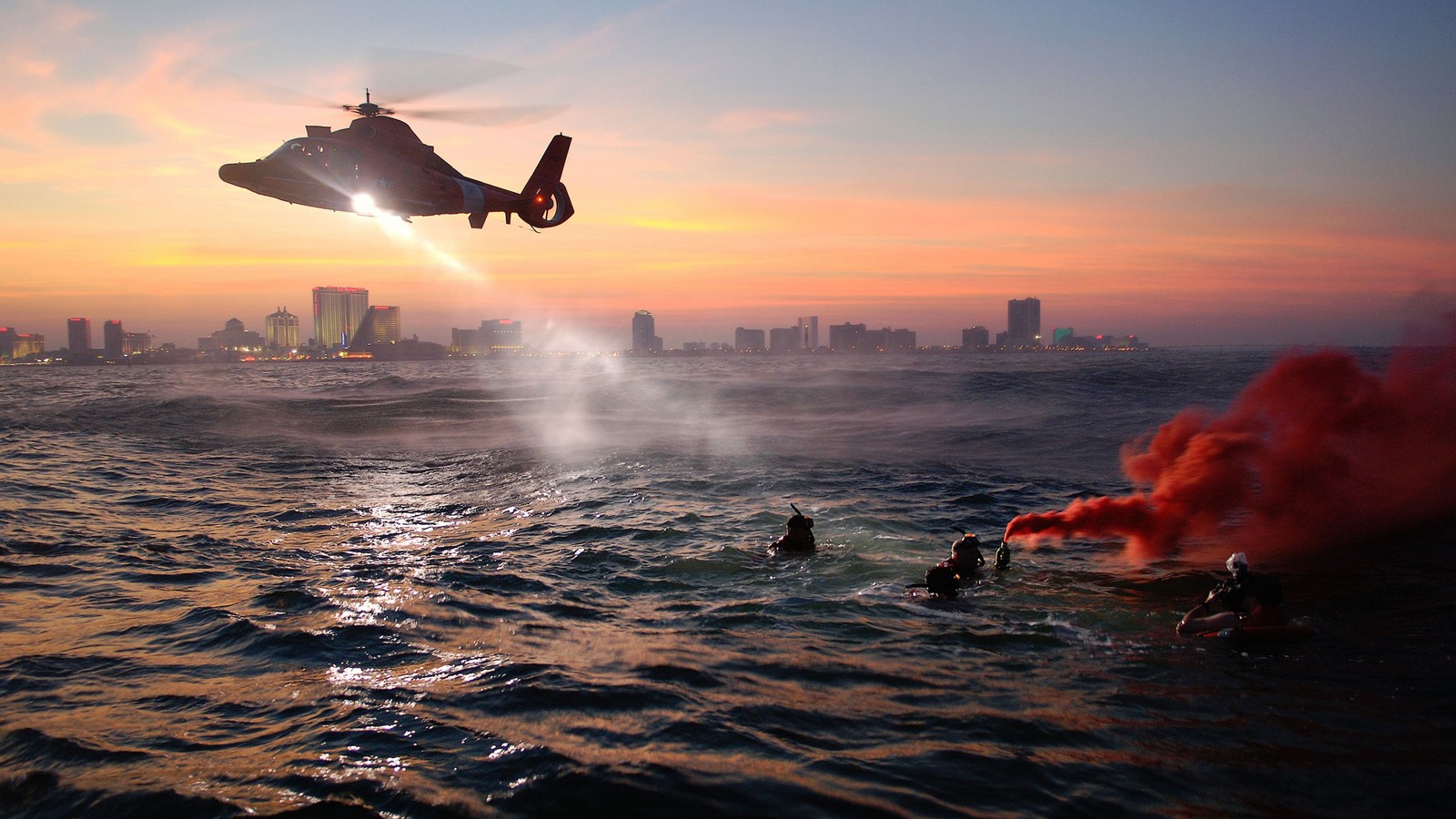 Ein hubschrauber fliegt über ein gewässer mit einer stadt im hintergrund (sonnenuntergang, welle, meer, horizont, flug)