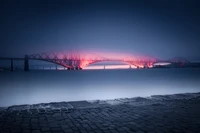 Illuminated Forth Bridge at Dusk Over the River