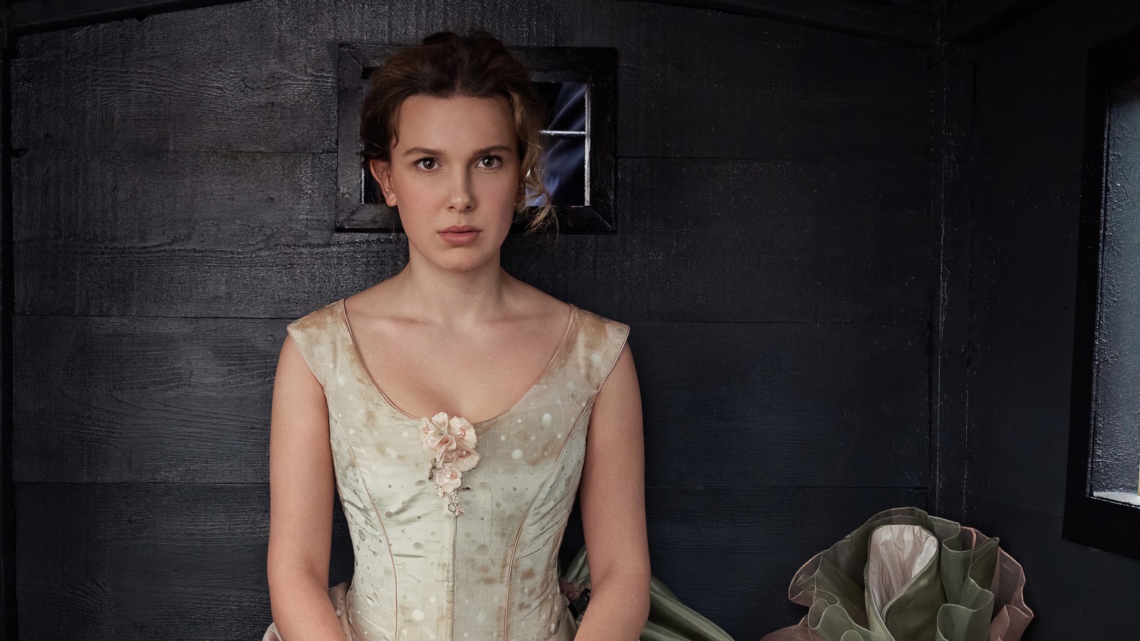 Il y a une femme en robe debout dans une pièce (enola holmes 2, netflix, série télévisée, millie bobby brown)