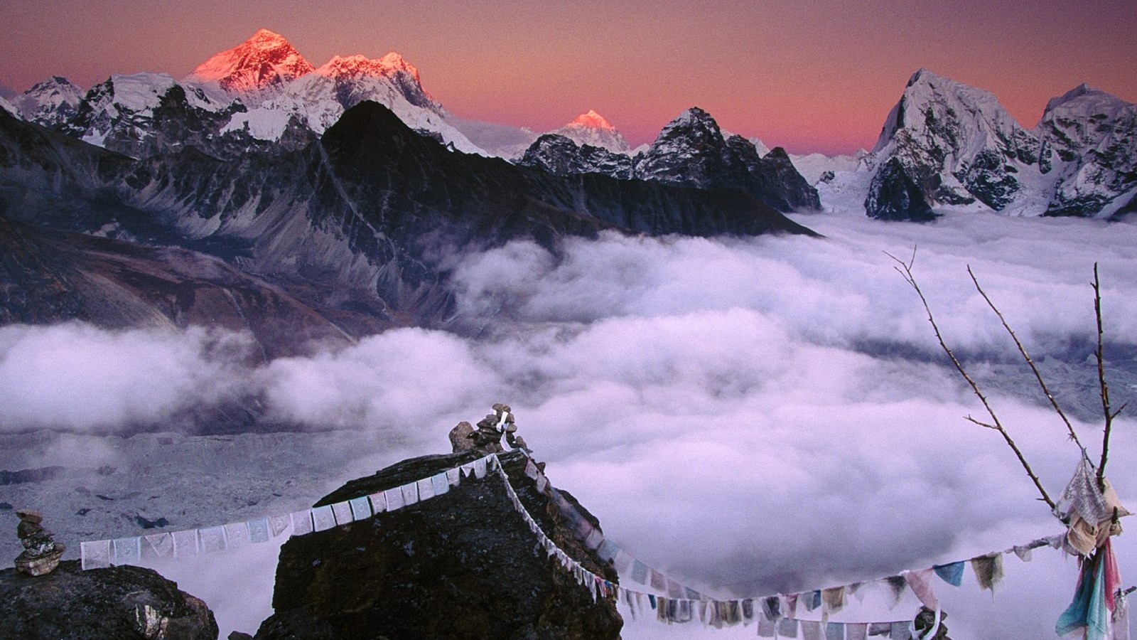 Montagnes couvertes de neige et de nuages avec des drapeaux de prière suspendus (mont everest, montagne, formes montagneuses, nature, chaîne de montagnes)