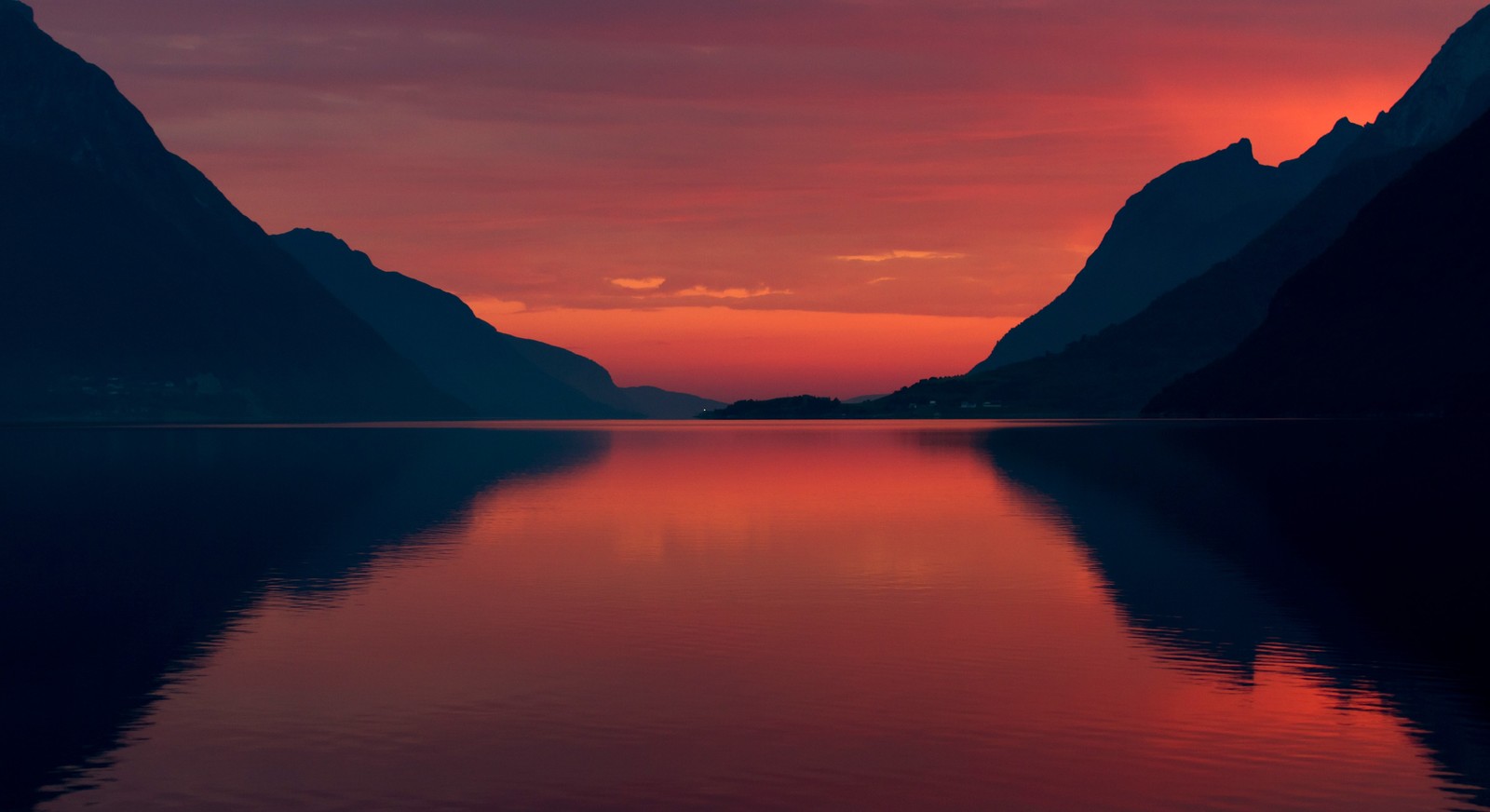 Uma vista de um lago com montanhas ao fundo ao pôr do sol (natureza, reflexo, resplendor, lago, por do sol)