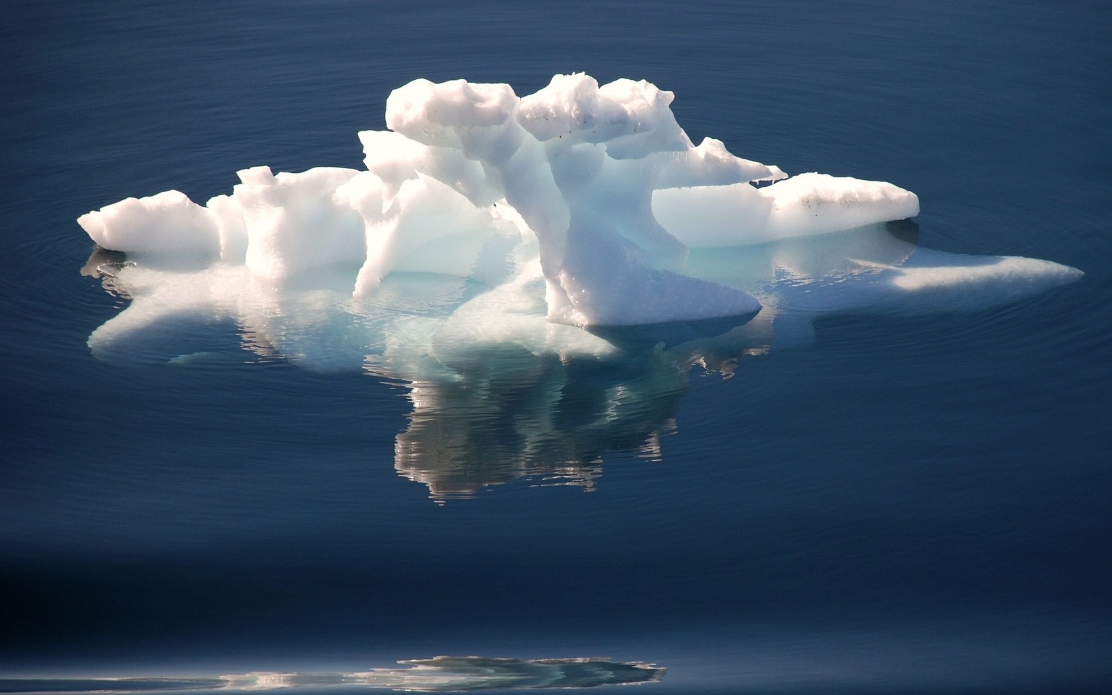 Il y a un grand iceberg flottant dans l'eau avec une petite île en arrière-plan (iceberg, nuage, cumulus, glace, glace de mer)