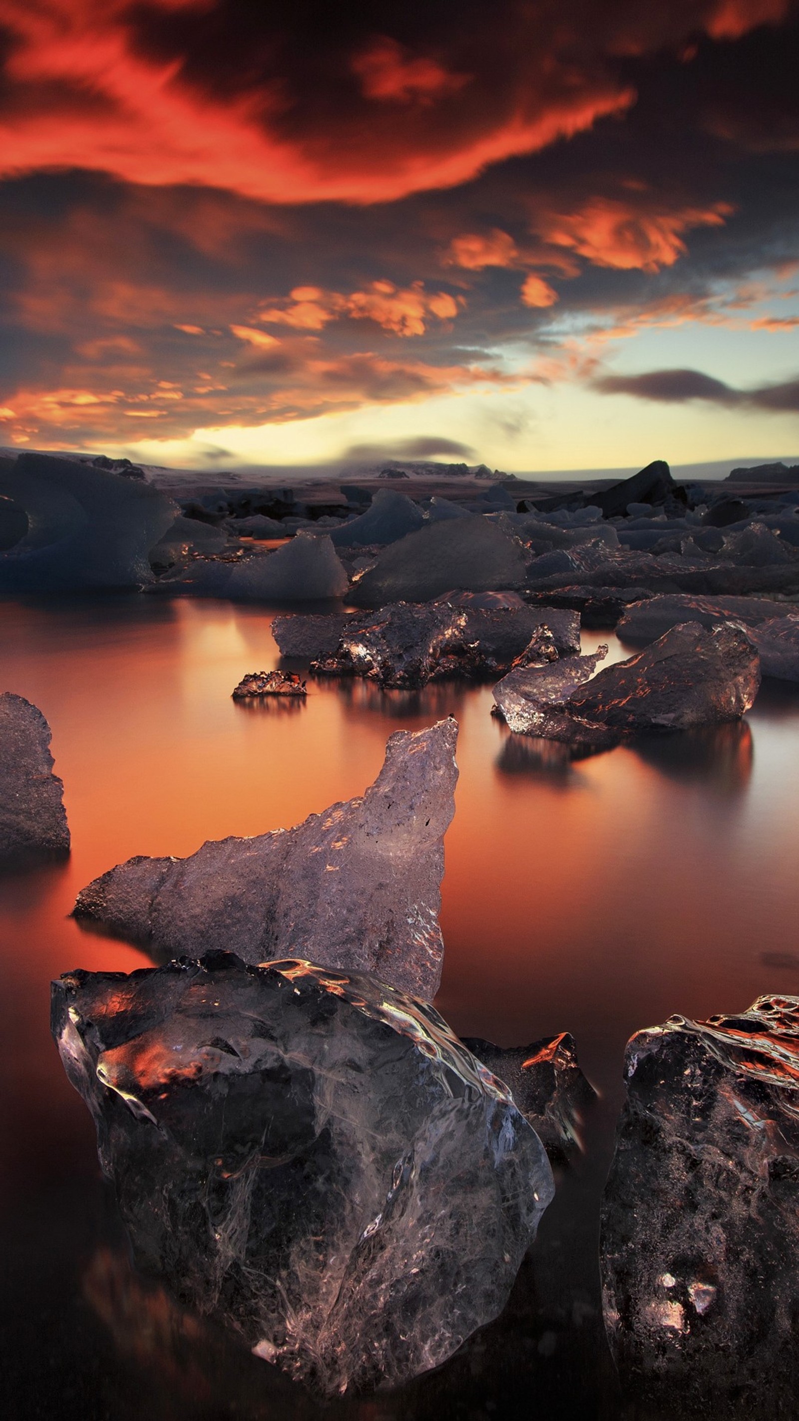 Des icebergs fondus flottant dans un lac avec un coucher de soleil en arrière-plan (lagune, eau, horizon, réflexion, ciel)