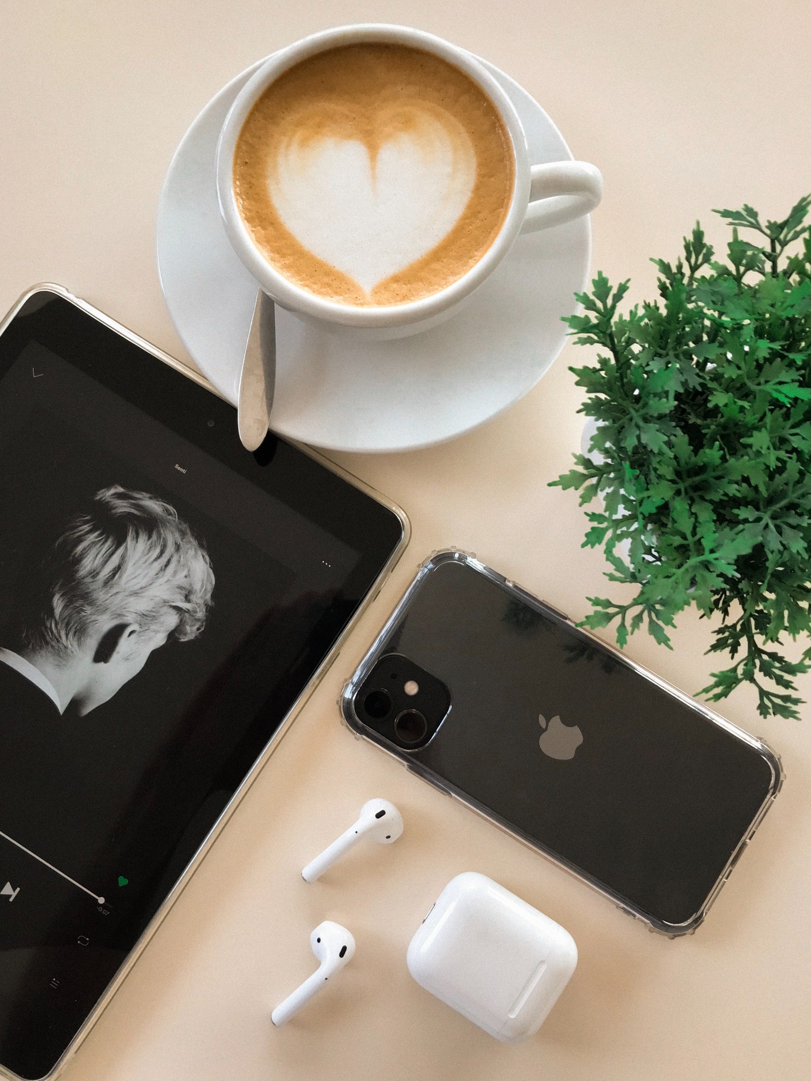 Una taza de café, un teléfono celular y unos apple airpods sobre una mesa (airpods, manzana, café, diseño, buen)