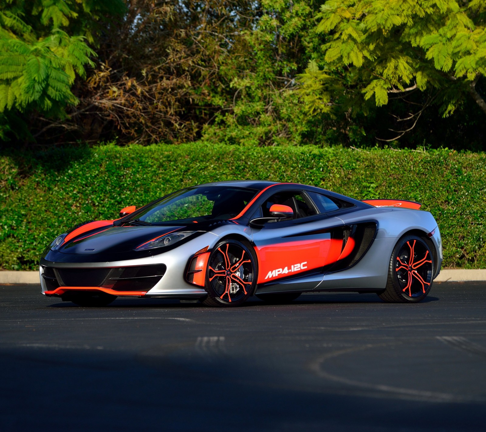 A close up of a silver and orange sports car parked in a parking lot (black, britain, england, mclaren, orange)