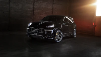 Elegante Porsche Cayenne negro exhibido en un entorno industrial débilmente iluminado, destacando su diseño moderno y su parrilla distintiva.