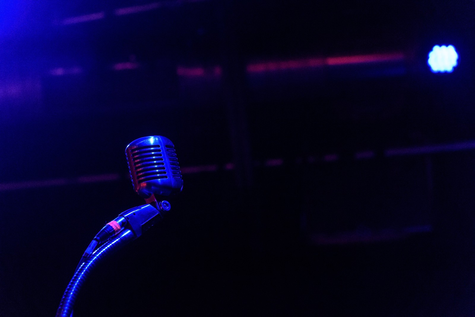 Arafed microphone on a stand in front of a stage with blue lights (microphone, blue, violet, light, performance)