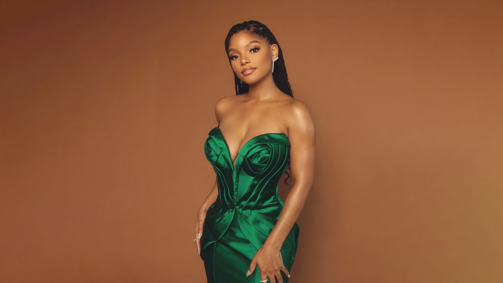 Une femme en robe verte posant pour une photo (halle bailey, 5k, actrice américaine, arrière plan brun, gens)