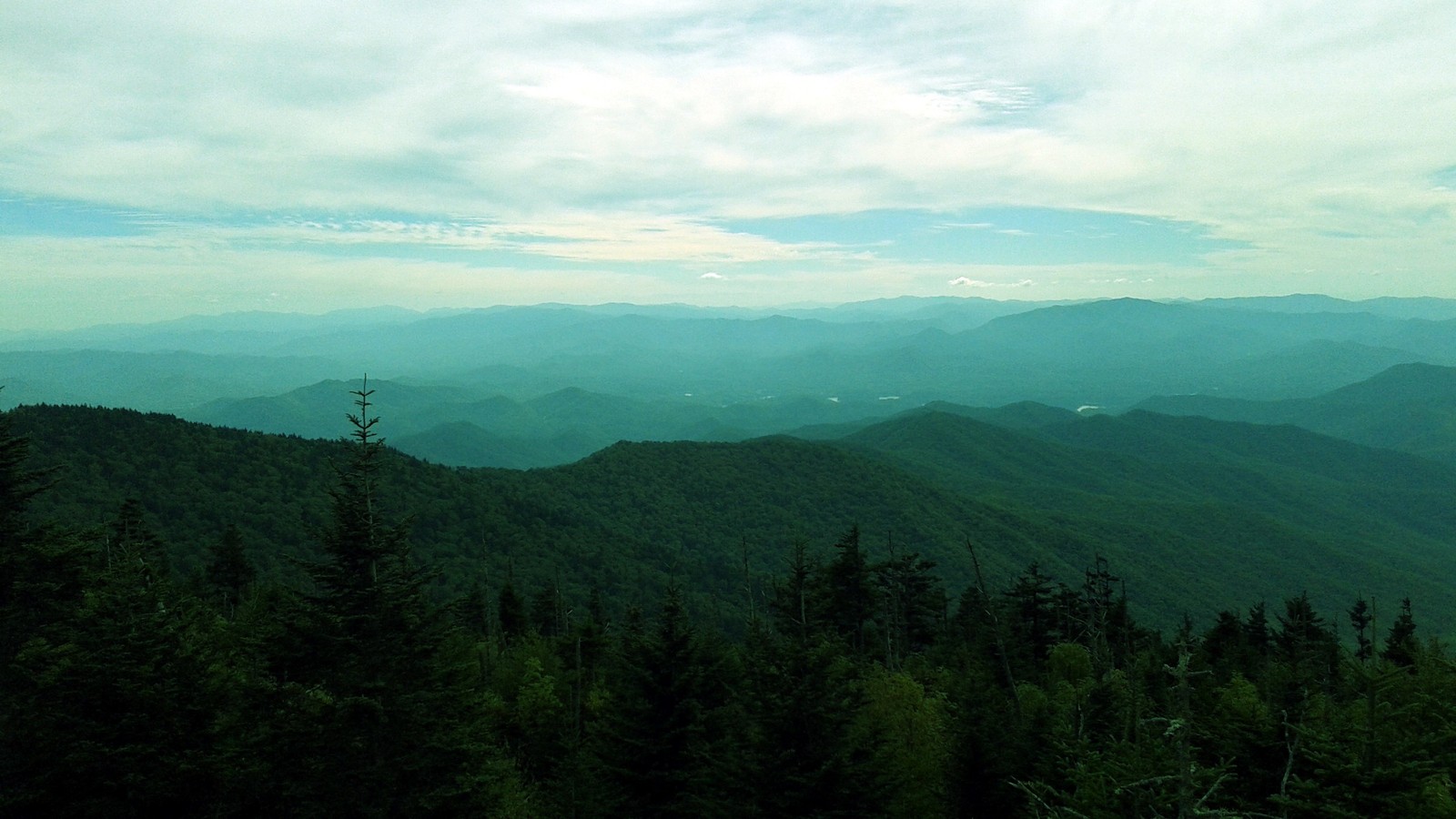 Uma vista árabe de uma cadeia de montanhas com algumas árvores (montanha, formas montanhosas, verde, terras altas, crista)