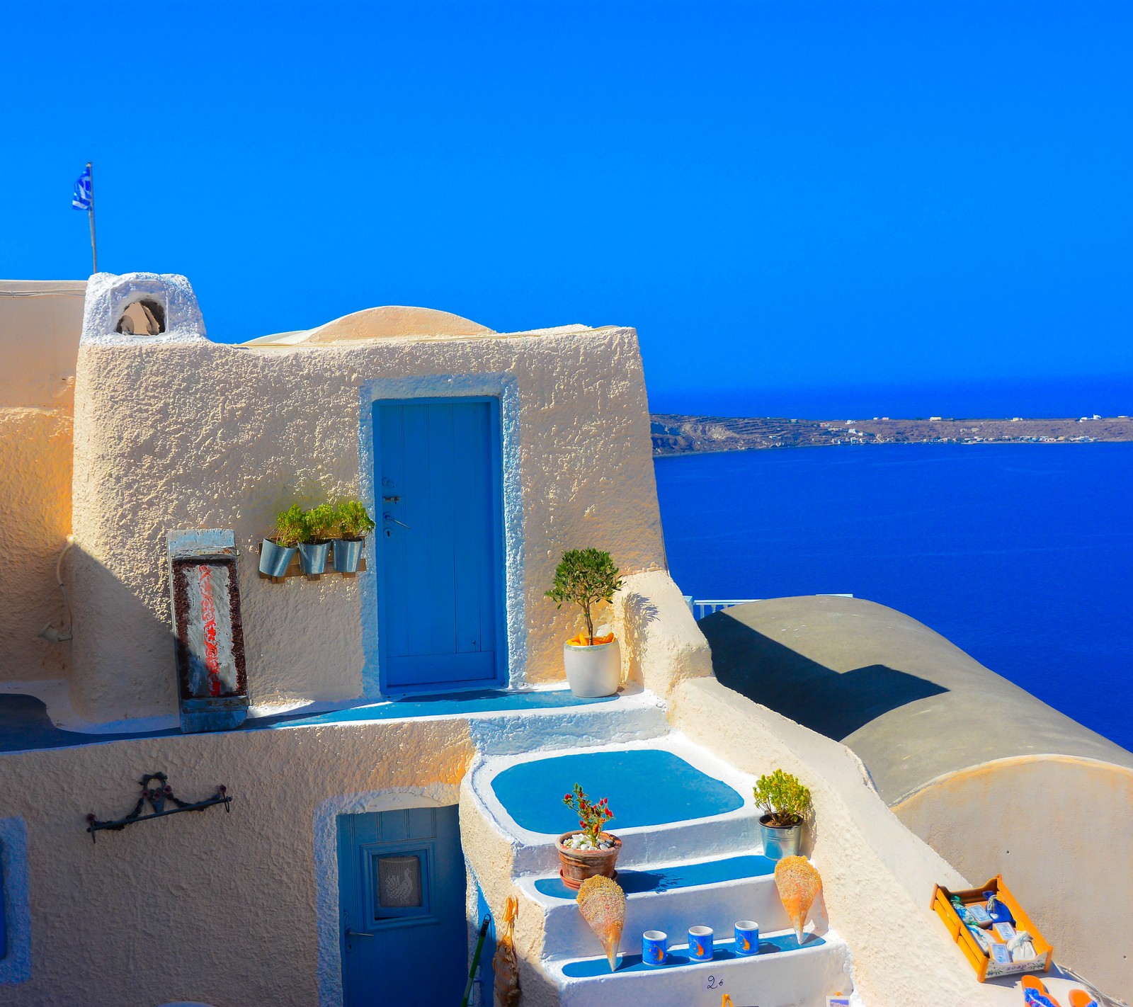 Há uma porta azul e uma janela azul em um edifício branco (grécia, ilha, santorini, viagem)