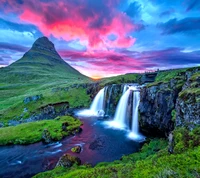 Cascada majestuosa al anochecer con cielo vibrante y fondo montañoso