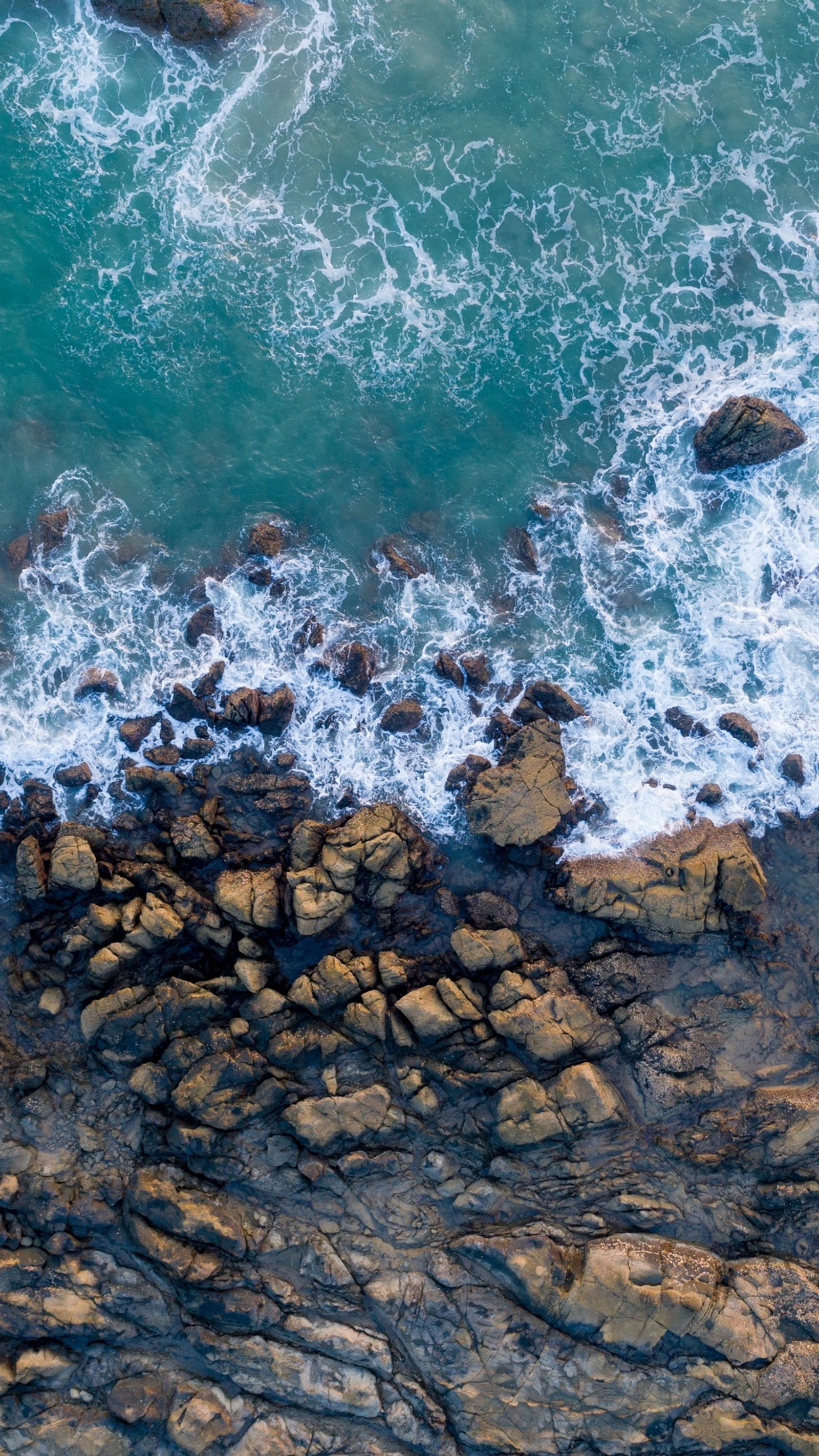 Vista aérea de um surfista pegando uma onda nas rochas (magia, água)