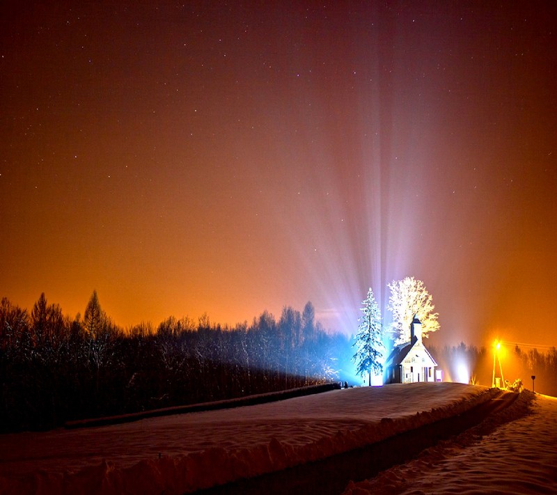 Snowy road with a light beam in the sky and a tree in the foreground (nature)