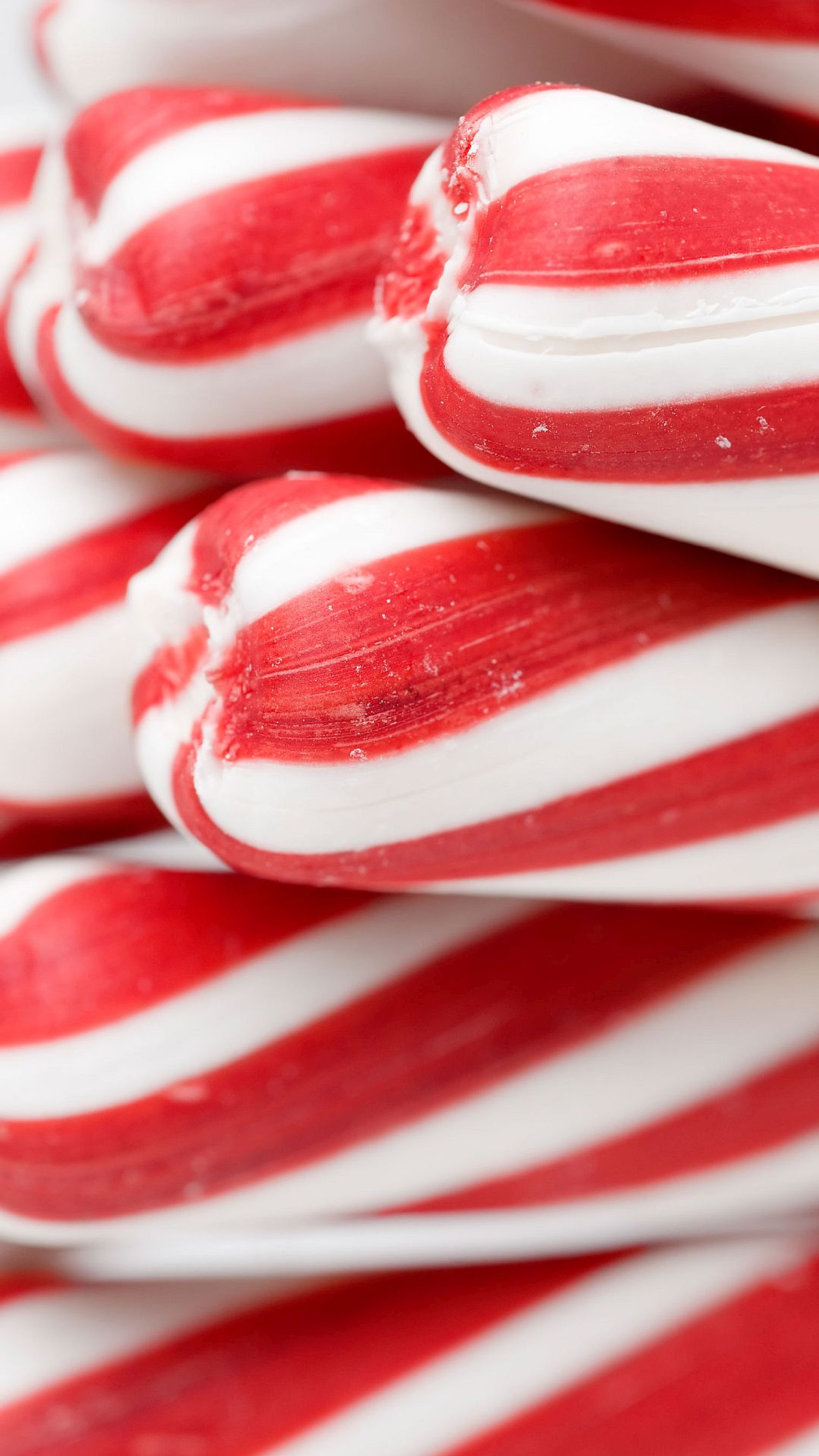 Il y a de nombreux sucres d'orge empilés sur une table (bonbons, canne en sucre, joyeux noël, peppermint)