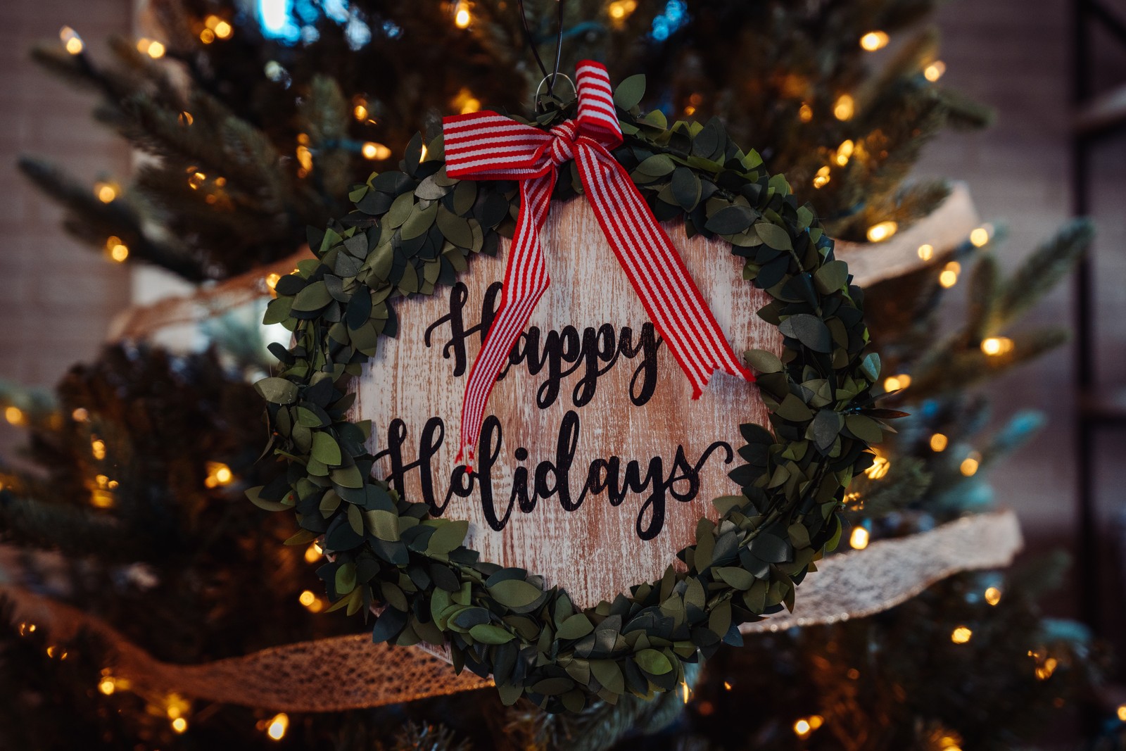 Un primer plano de una corona de navidad colgando de un árbol de navidad (nuevo año, día de navidad, festivo, adorno de navidad, navidad)