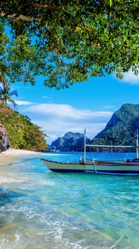 Paisaje de playa sereno con barco y montañas exuberantes bajo un cielo azul