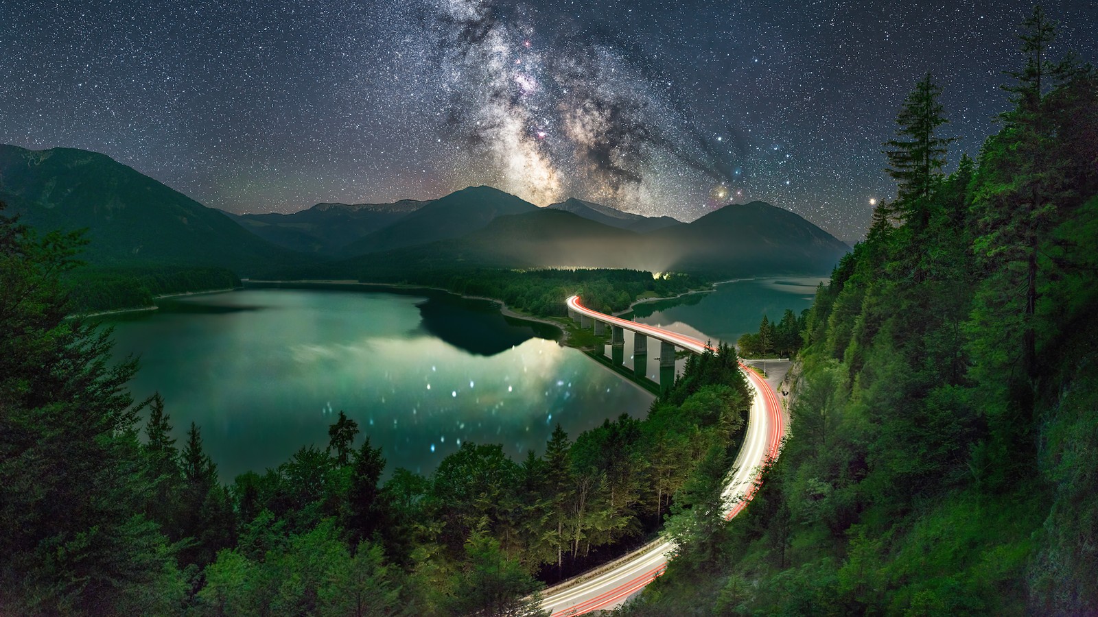 Uma longa exposição de uma estrada passando sobre um lago sob um céu estrelado (água, planta, recursos hídricos, mundo, luz)