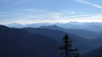 Chaîne de montagnes majestueuse sous un ciel bleu clair, présentant des crêtes escarpées et une nature sauvage sereine.