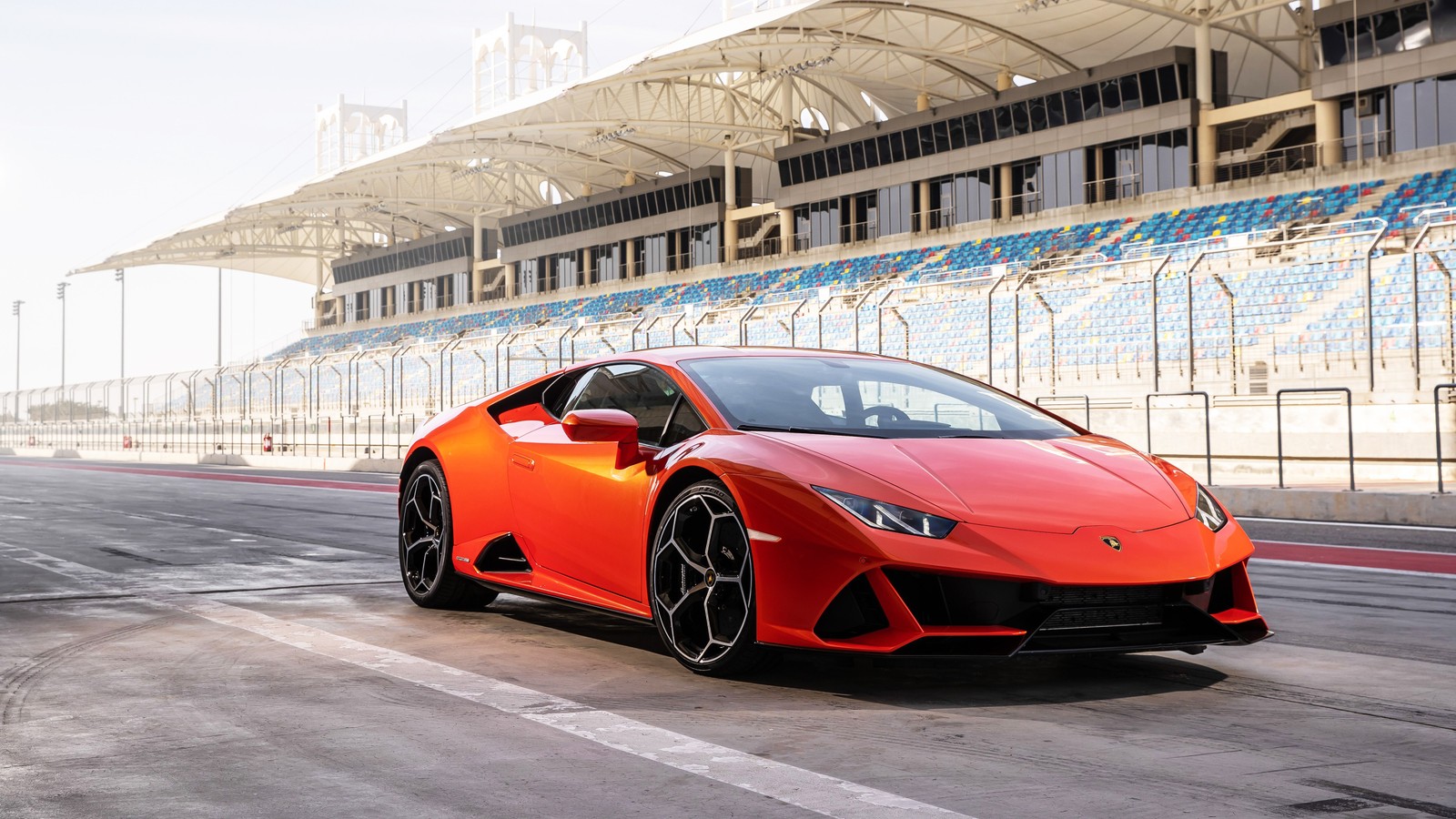 Une voiture de sport rouge roulant sur une piste avec un stade en arrière-plan (lamborghini urus, lamborghini, voitures, voiture de sport, supersportive)