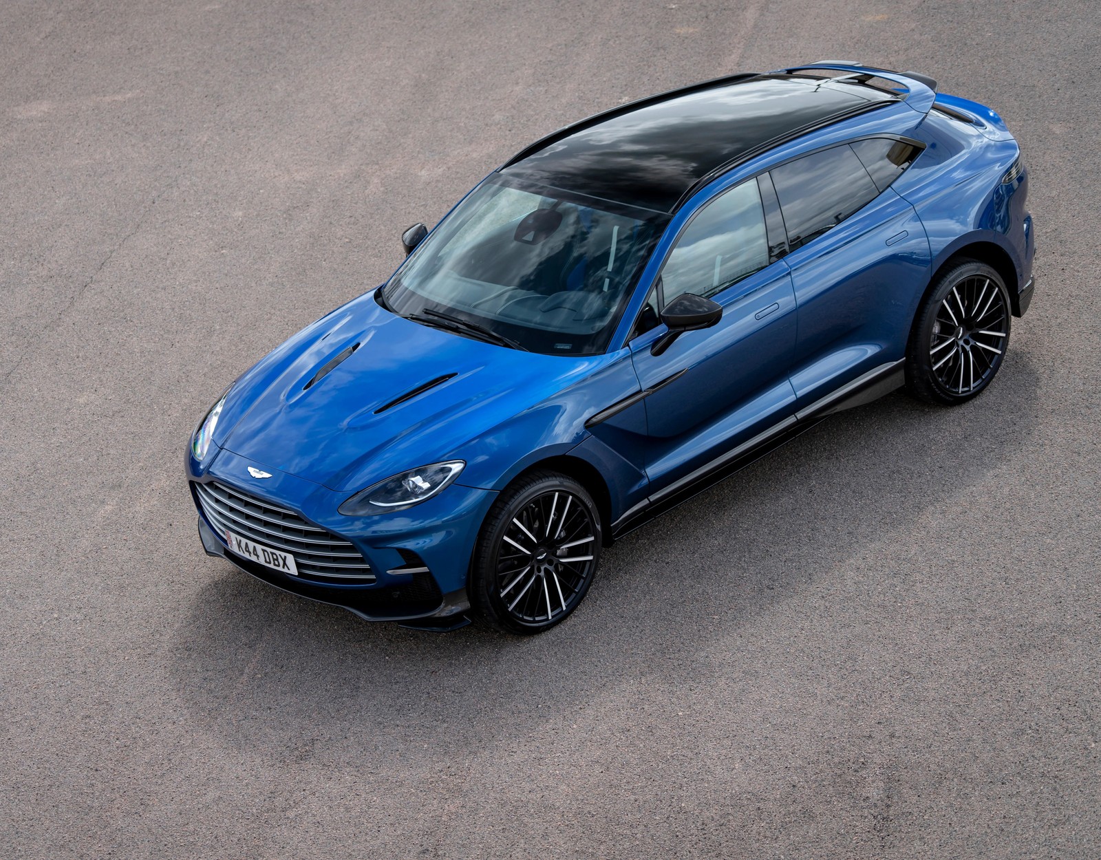 Un coche azul está conduciendo por una carretera con un fondo de cielo (aston martin dbx707, suv de lujo, 2022, 5k, coches)