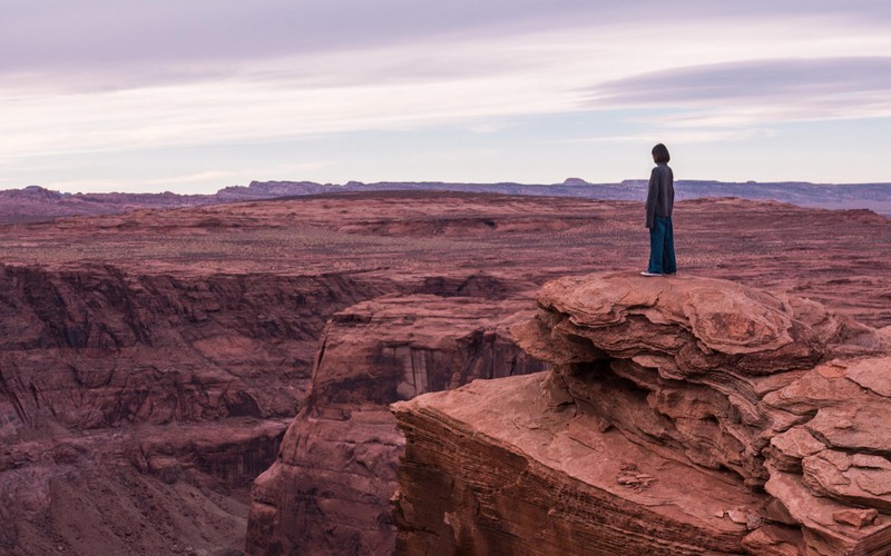 Арафе, стоящий на утесе с видом на каньон и небо (изгиб лошадиная подкова, horseshoe bend, гранд каньон, grand canyon, бедлендс)