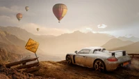 Porsche Carrera GT mit Blick auf eine malerische Landschaft mit Heißluftballons