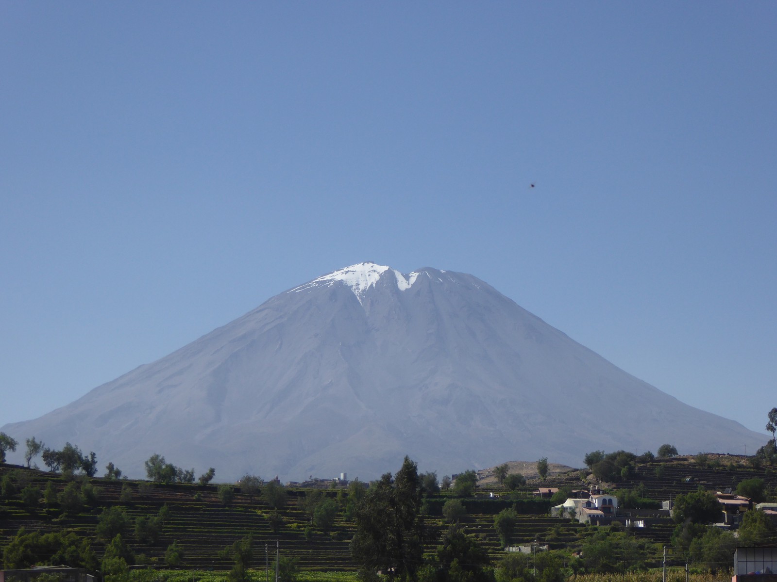 Montanha com um pico coberto de neve ao longe (estratovulcão, cenário de montanha, montanha, vulcão extinto, relevo vulcânico)