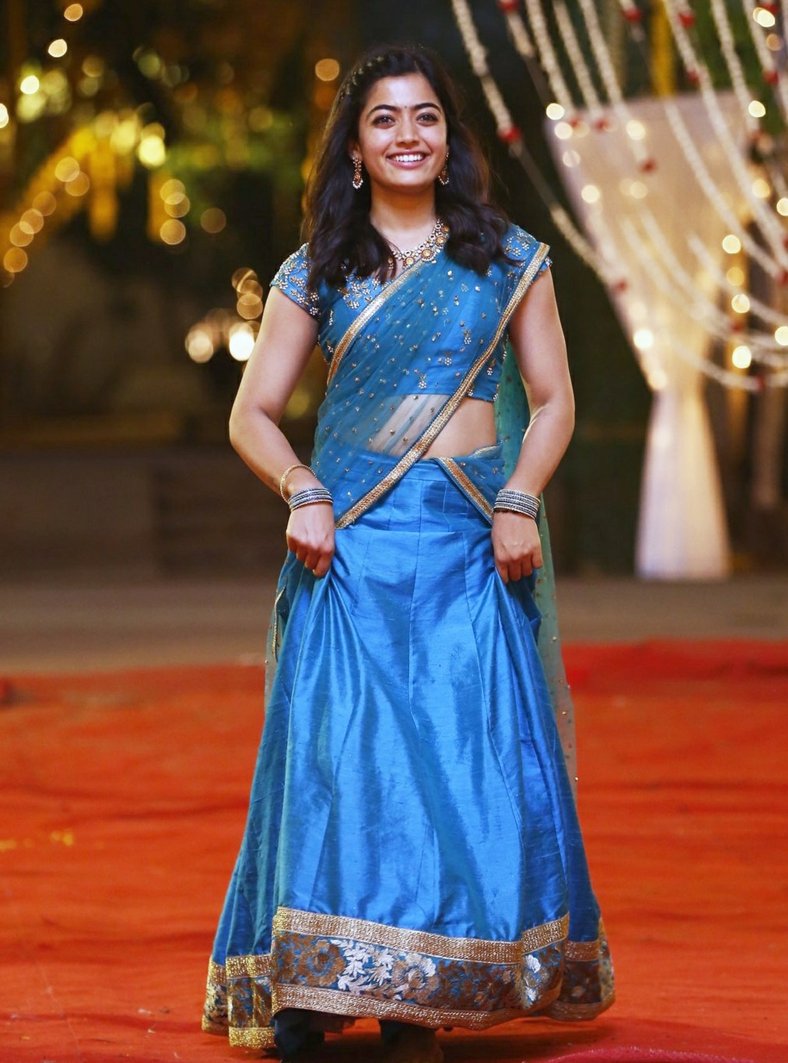 Une femme en sari bleu et blouse dorée debout sur un tapis rouge (actrice, kannada, rashmika, rashmika mandanna, rashmika mandana)