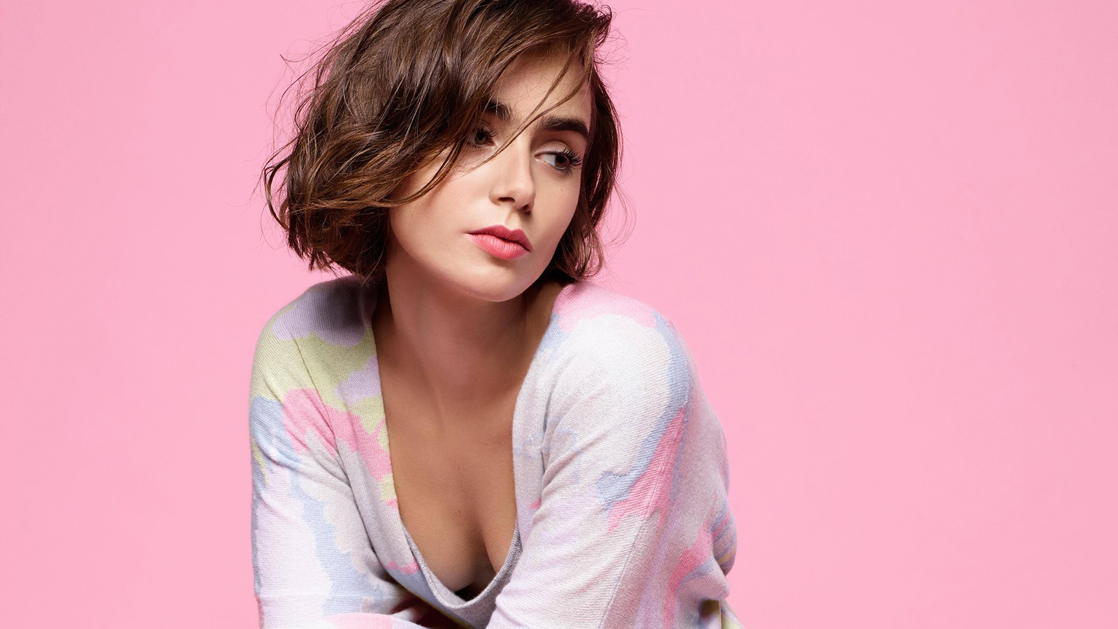 Un gros plan d'une femme assise sur un tabouret avec un fond rose (lily collins, beau, actrice, femmes, filles)