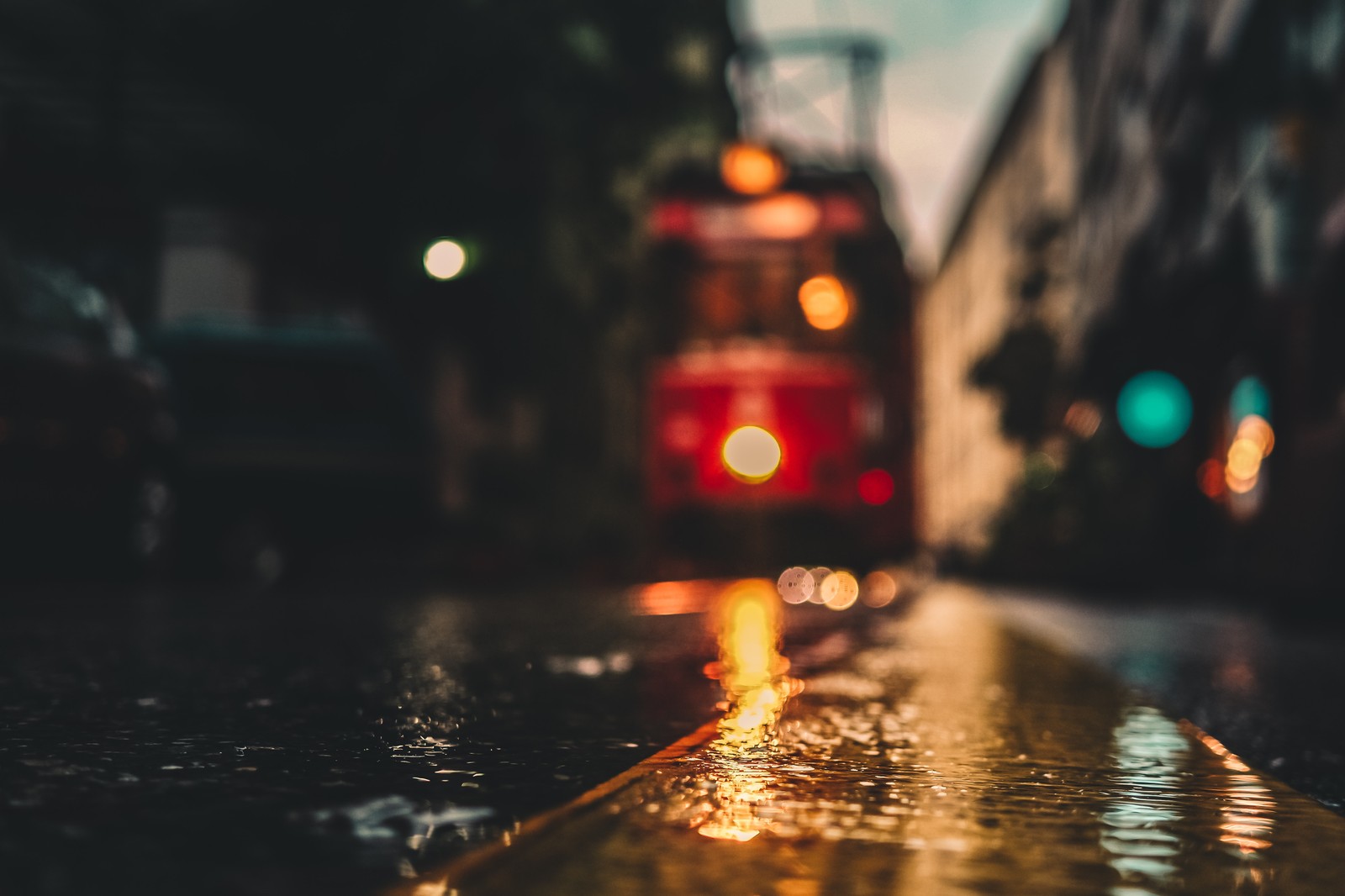 Arafed view of a red train on a city street at night (lighting, water, red, light, reflection)