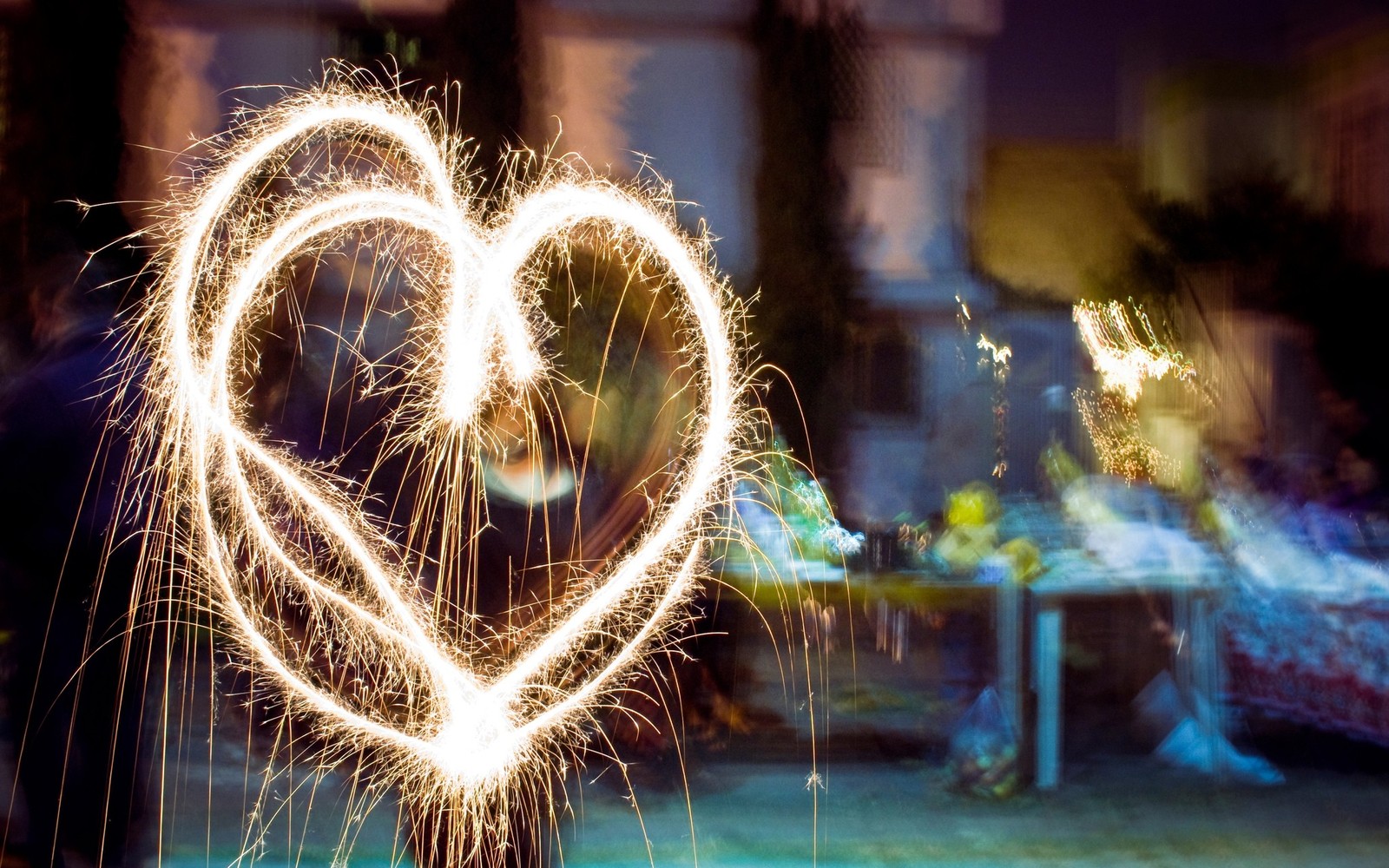 Gros plan d'une personne tenant une étincelle en forme de cœur (noël, pétard, lumière, amour, cœur)