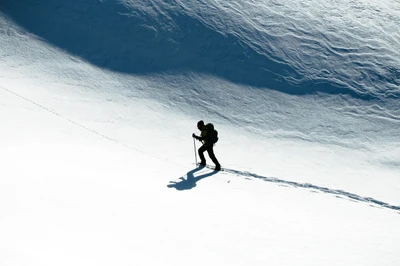 Ein alleinstehender Skifahrer steigt einen verschneiten Hang hinauf