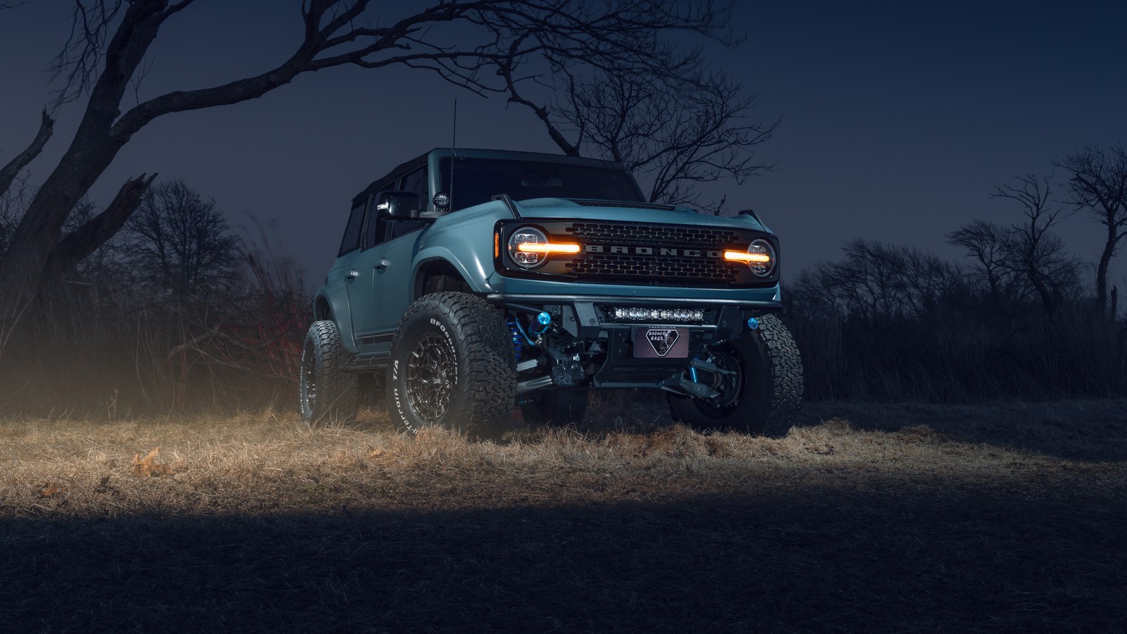 Un gros plan d'un camion bleu garé dans un champ la nuit (ford bronco, nuit, séance photo, voitures, fond décran 4k)