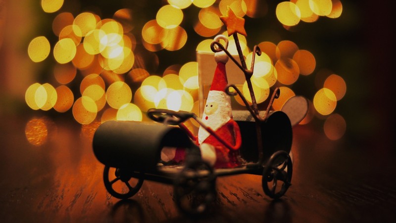 Il y a une petite voiture jouet avec un père noël dessus (lumière, lumières de noël, éclairage, noël, amusement)