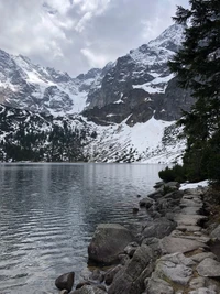 Sereno lago glacial rodeado de montañas cubiertas de nieve y valles exuberantes.