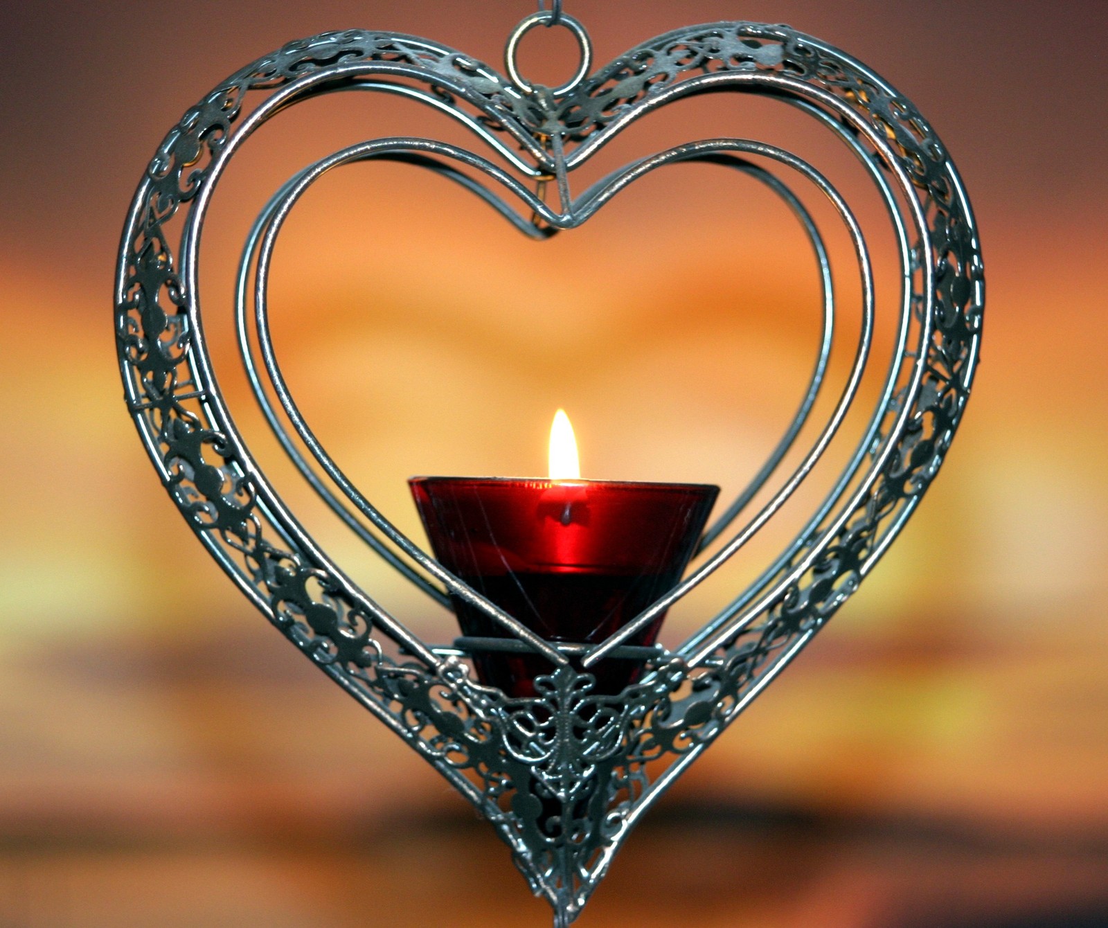 Hay una vela encendida en un candelabro en forma de corazón (vela, corazón, amor, rojo, romántico)