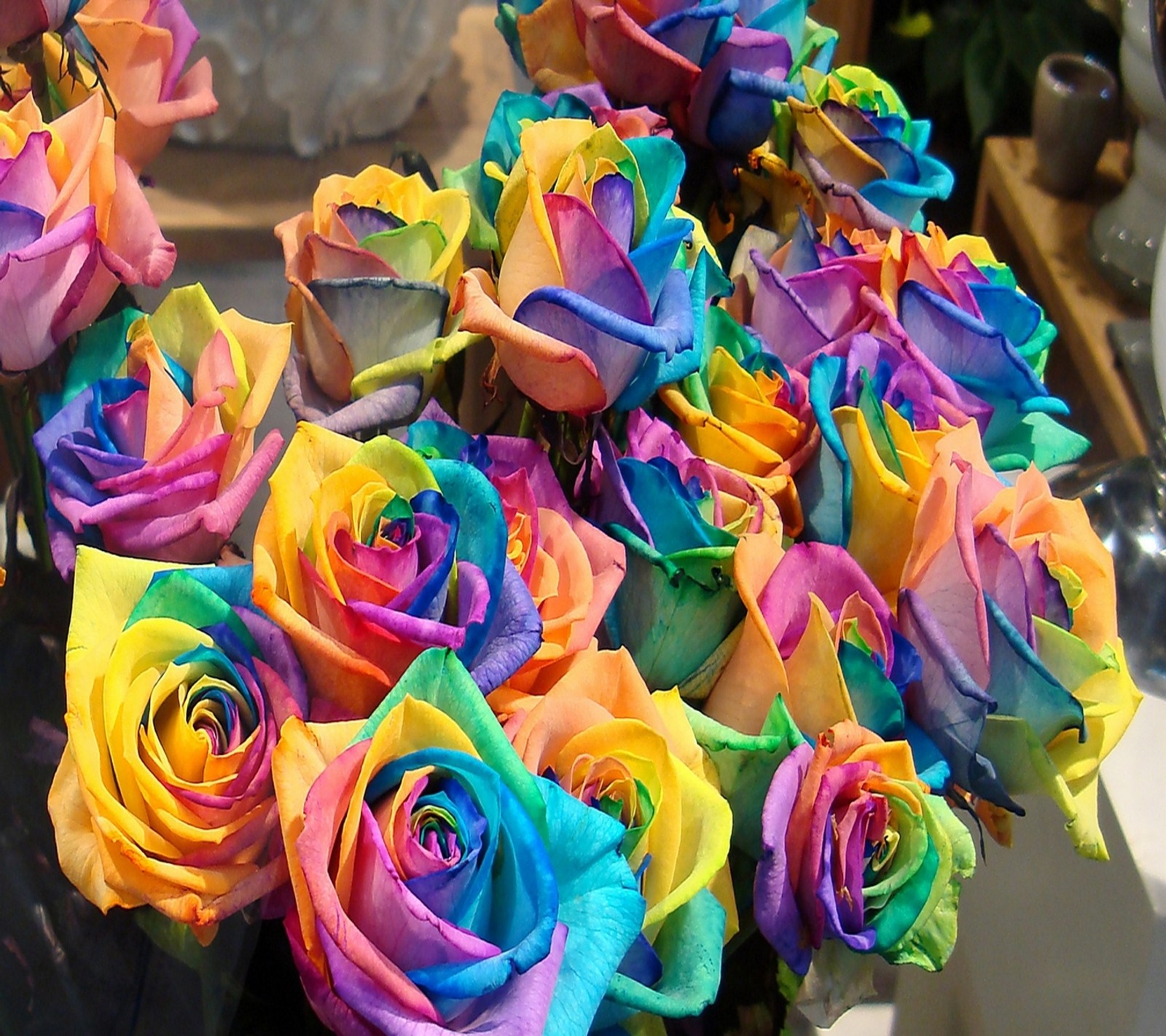 Rosas coloridas estão arranjadas em um vaso em uma mesa (colorido, flores)